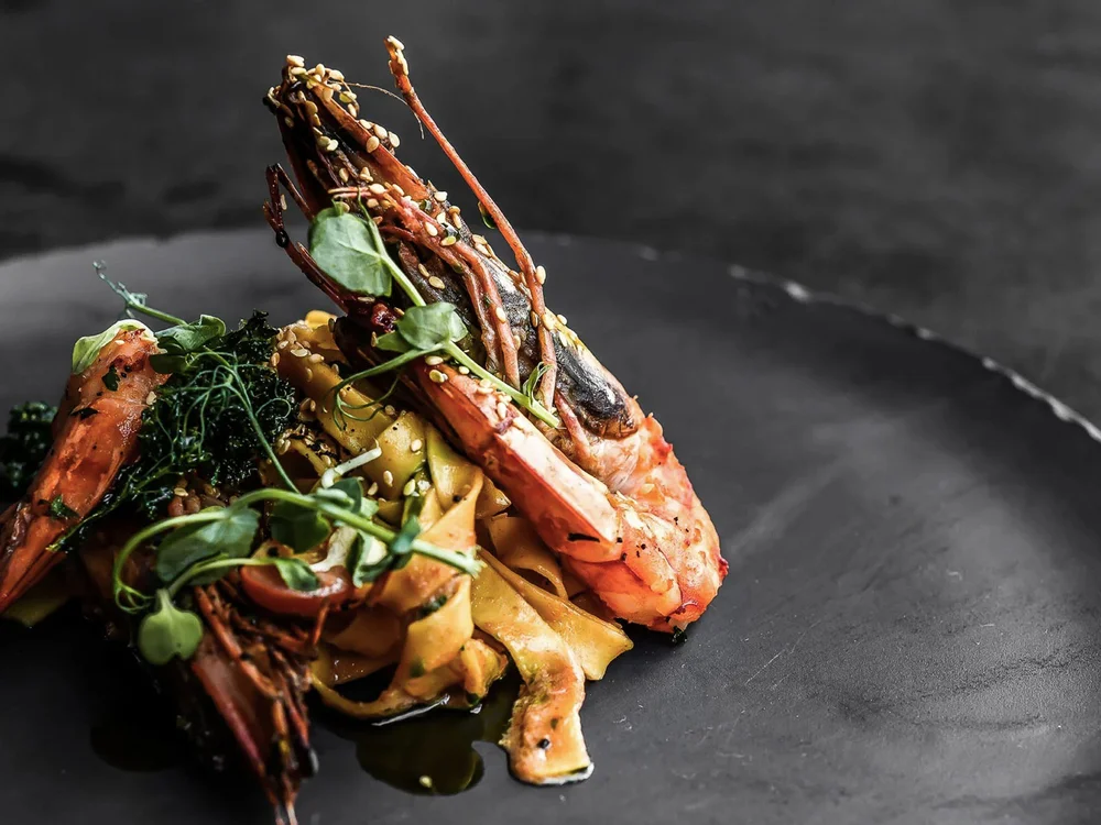 Hotel Salnerhof | 4 Sterne Superior in Ischgl Gegrillte Garnelen auf Bandnudeln mit Kräutern auf schwarzem Teller