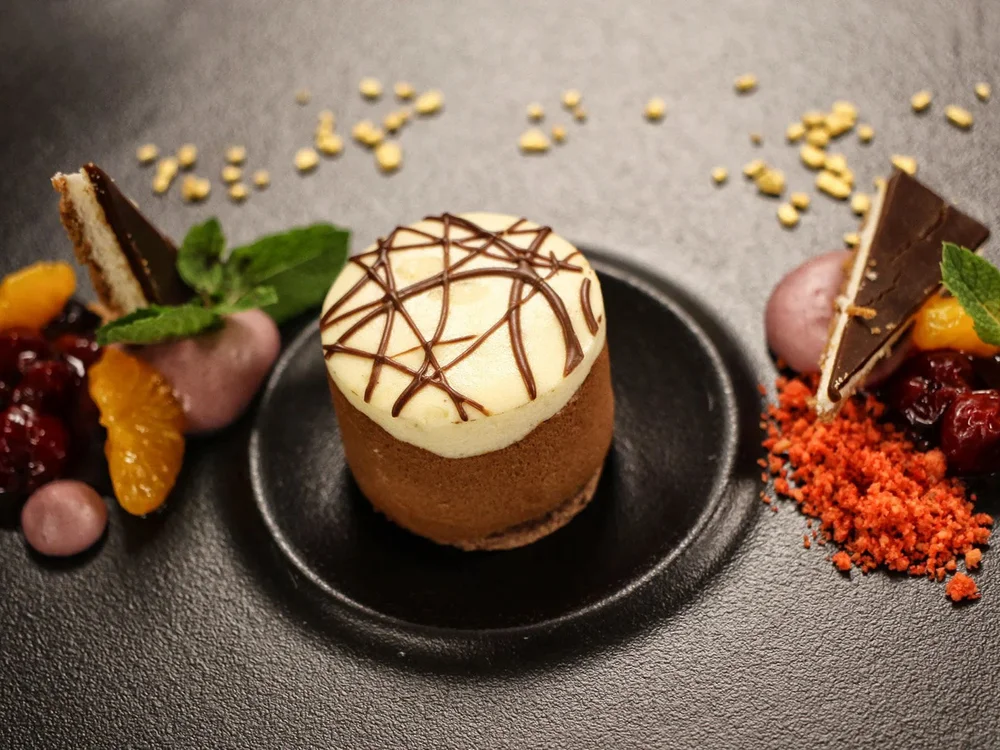 Hotel Salnerhof | 4 Sterne Superior in Ischgl Fein dekoriertes Dessert mit Schokolade, Früchten und Minze auf schwarzem Teller