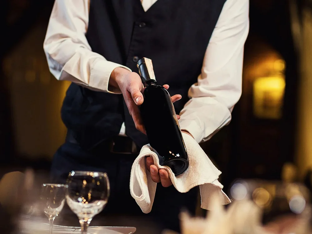 Hotel Salnerhof | 4 Sterne Superior in Ischgl Kellner präsentiert eine Weinflasche in einem Restaurant