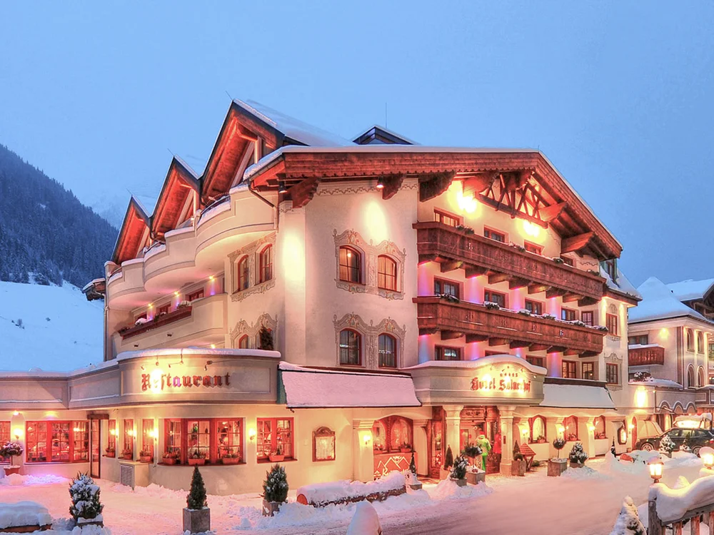 Hotel Salnerhof | 4 Sterne Superior in Ischgl Beleuchtetes Hotel in verschneiter Berglandschaft bei Abenddämmerung