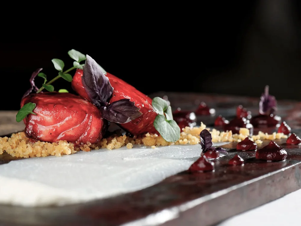 Hotel Salnerhof | 4 Sterne Superior in Ischgl Kreativ angerichtetes Gourmetgericht mit roten Früchten und Kräutern auf schwarzem Teller