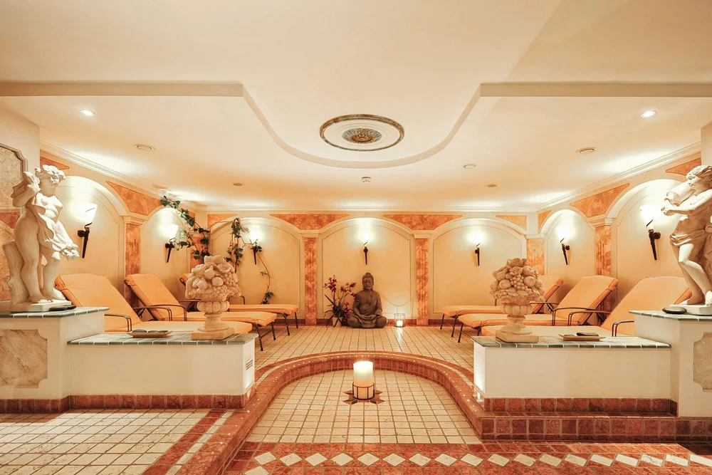 Eleganter Wellnessraum mit Liegestühlen, Statuen und Kerzenbeleuchtung