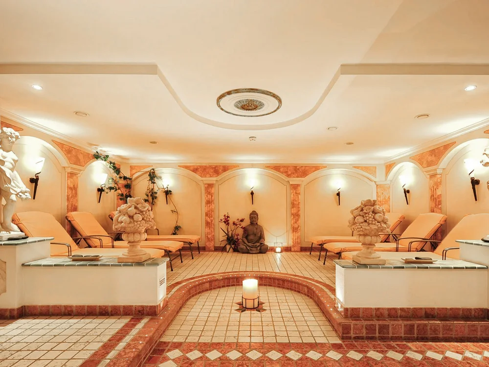 Hotel Salnerhof | 4 Sterne Superior in Ischgl Eleganter Wellnessraum mit Liegestühlen, Statuen und Kerzenbeleuchtung