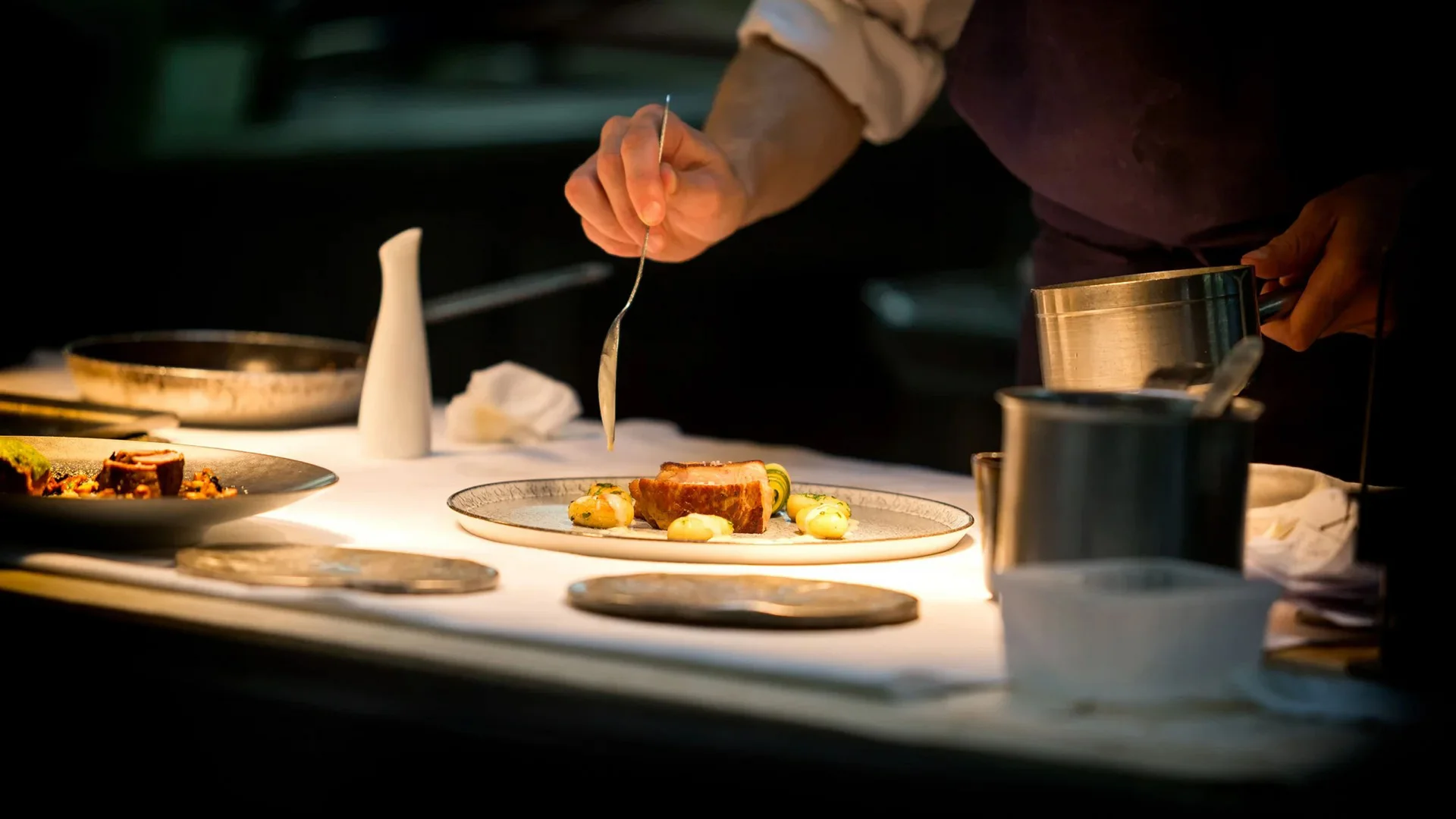 Koch richtet ein Gourmetgericht auf einem Teller in einer Restaurantküche an