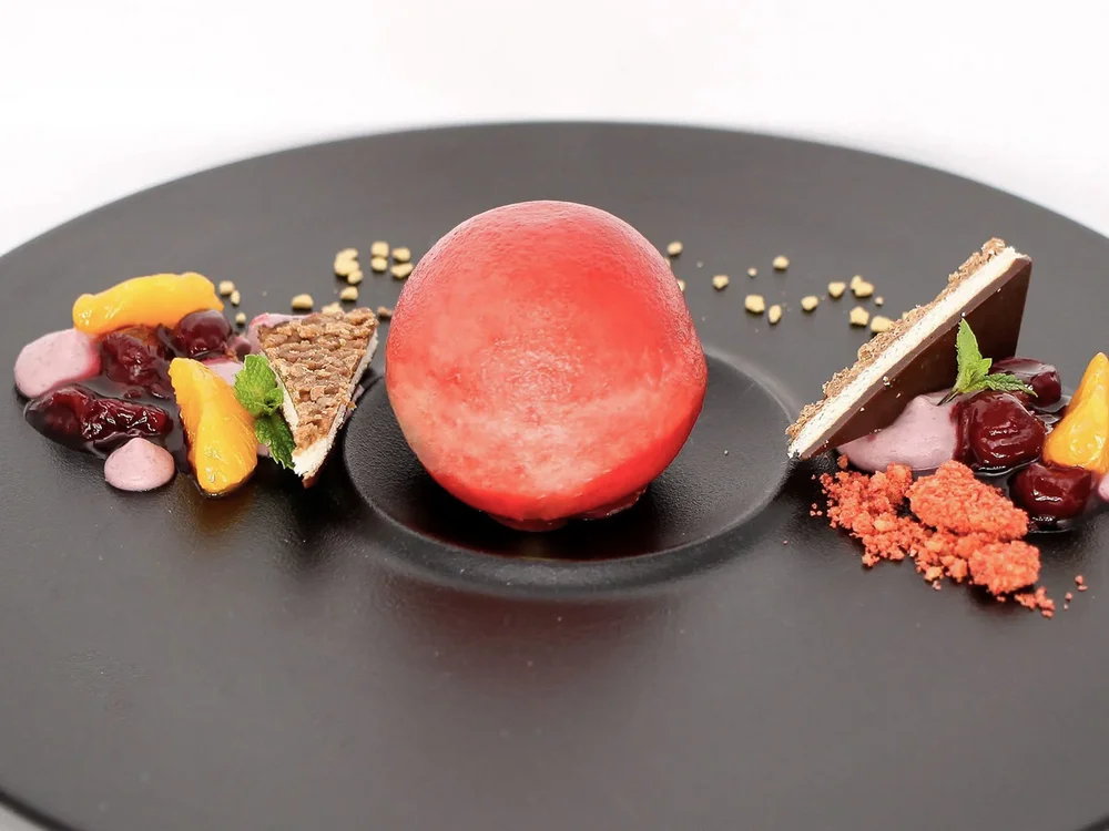 Hotel Salnerhof | 4 Sterne Superior in Ischgl Kunstvoll angerichtetes Dessert mit roter Kugel und Früchten auf schwarzem Teller