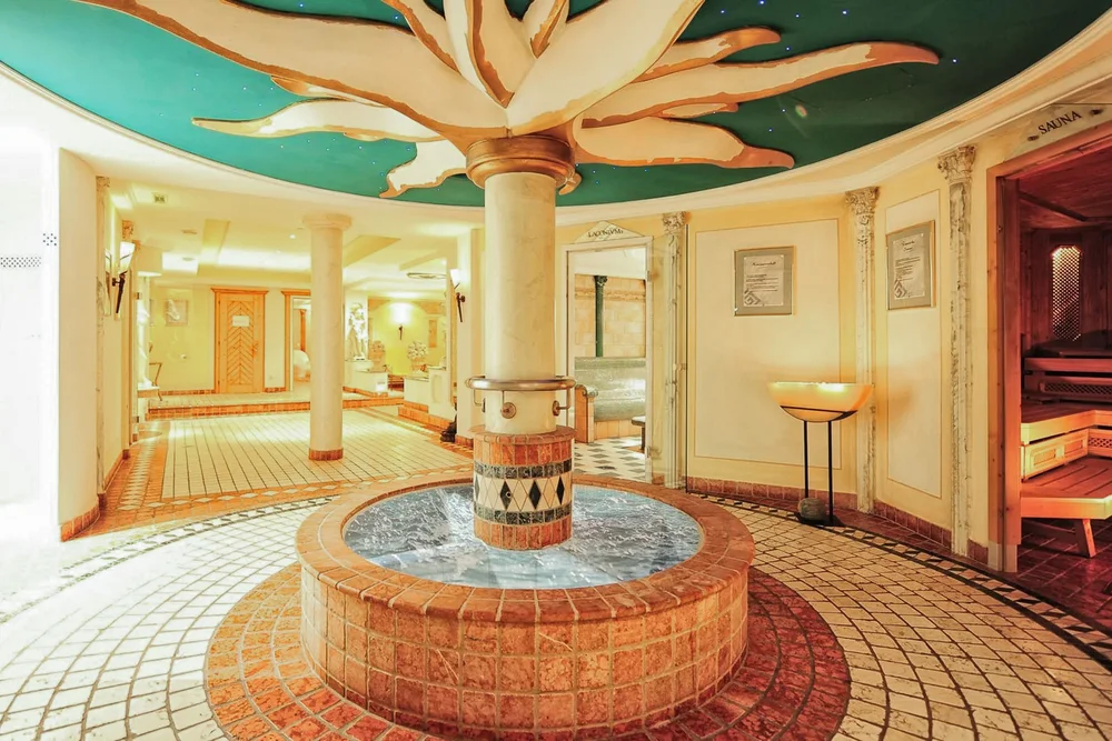 Innenansicht eines Wellnessbereichs mit Sauna und dekorativem Brunnen